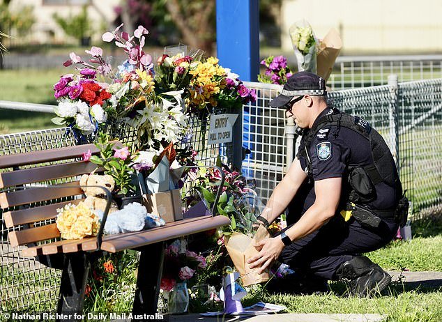 Officer at the makeshift memorial of flowers placed outside the Tara police station in the days after the police double shooting in Wiemabilla, 30 km north of the city.