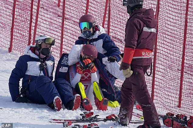 Team members comfort Mikaela Shiffrin of the United States after skiing in the first run of the women's slalom at the 2022 Winter Olympics