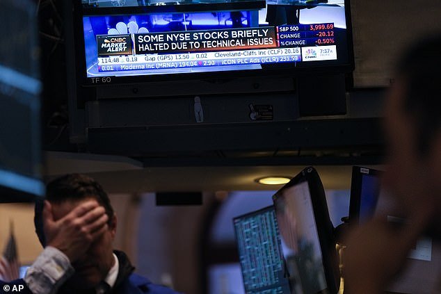 Traders look at screens indicating that some stocks have been stopped on the floor at the New York Stock Exchange