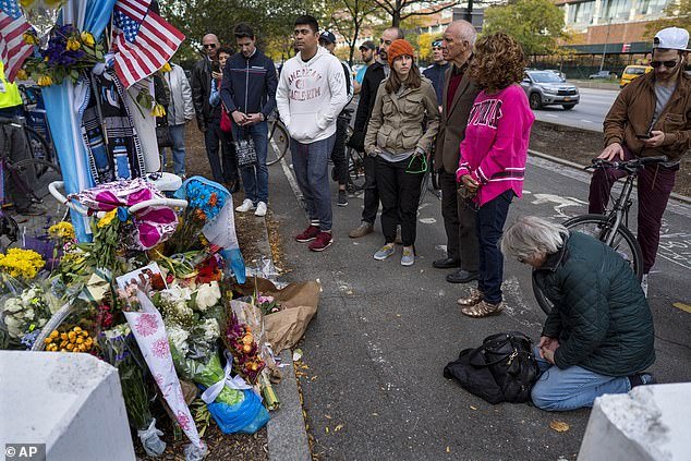 A group pauses, with some in prayer, at a makeshift memorial on a New York City bike path.
