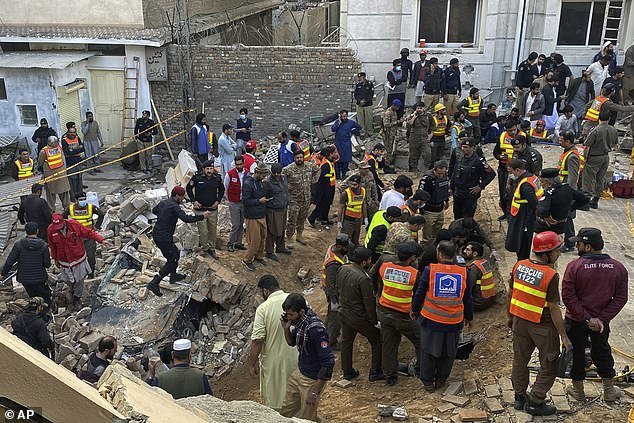 Security officials and rescue workers search for bodies at the site of suicide bombing in Peshawar on Monday
