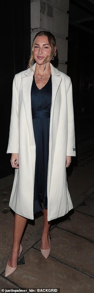 Gorgeous: Zara McDermott looked chic in a navy blue midi dress, with a long cream coat on top