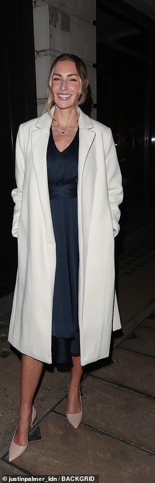 Gorgeous: Zara McDermott looked chic in a navy blue midi dress, with a long cream coat on top