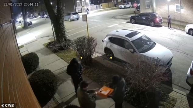 Surveillance footage captured the bizarre moment polite car thieves hold their victim's pizza while handing over the keys Saturday night in Chicago.