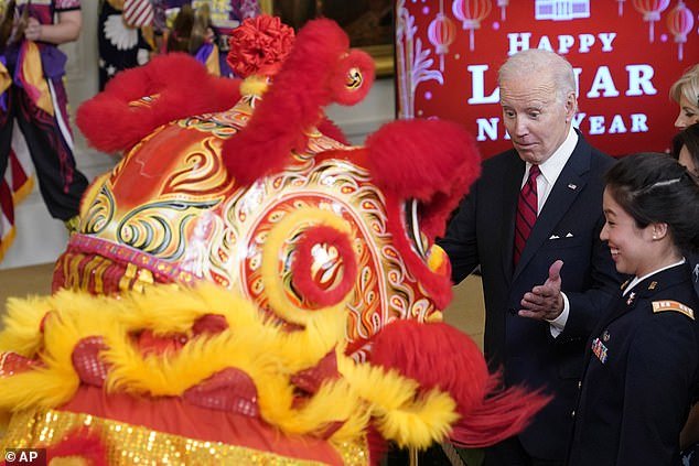 President Joe Biden watches the Choy Wun Lion Dance Company perform a dragon dance at the White House Lunar New Year celebration Thursday night.