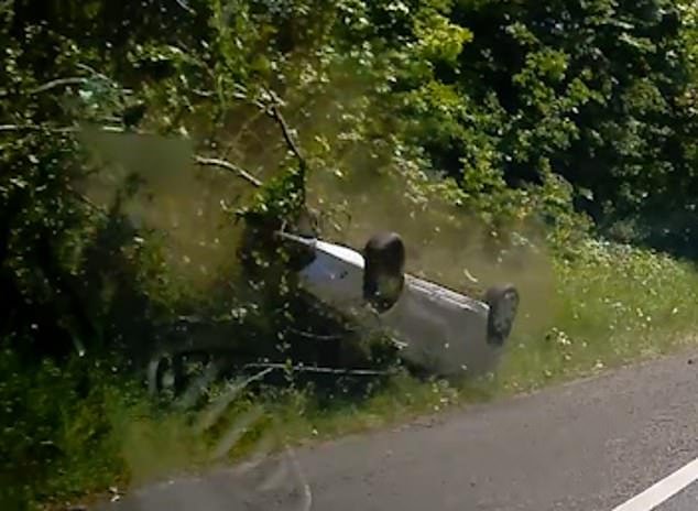 The car then accelerates up the bank, crashing into trees before flipping over and sliding down the berm onto the roof before coming to rest in the hard shoulder.