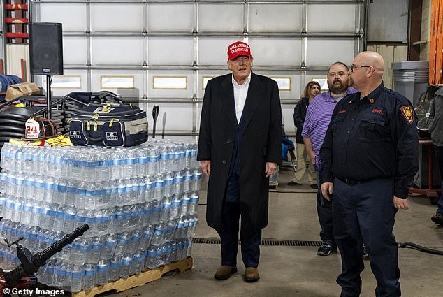 Trump stands next to a pallet of his branded water in eastern Palestine.  He brought trucks of his own supplies on his visit to the toxic train derailment site