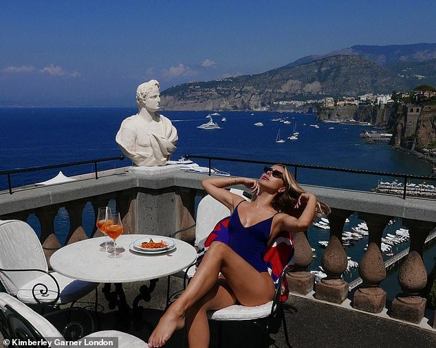Fun in the sun: The star put on a leggy show as she posed on a balcony in sunglasses