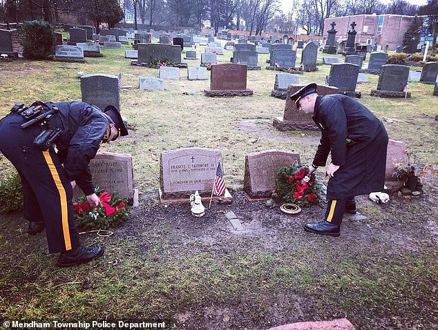 Officers play flowers at the cemetery where Baby Mary's final resting place is