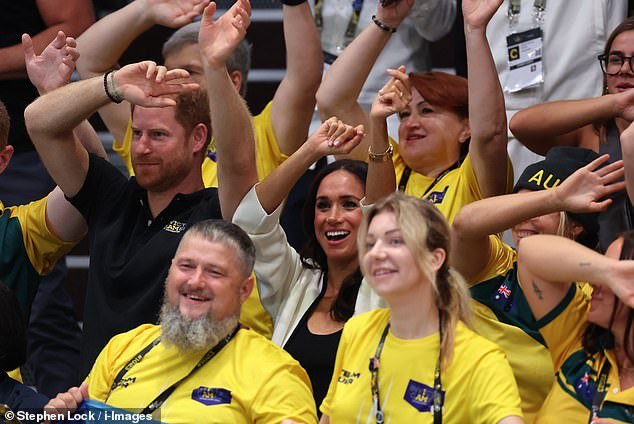 Prince Harry and Meghan Markle wave their hands during the wheelchair basketball match today