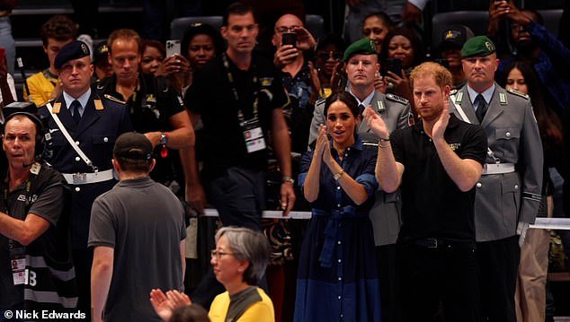Meghan appears overcome with emotion as she cheers on the veterans next to Prince Harry