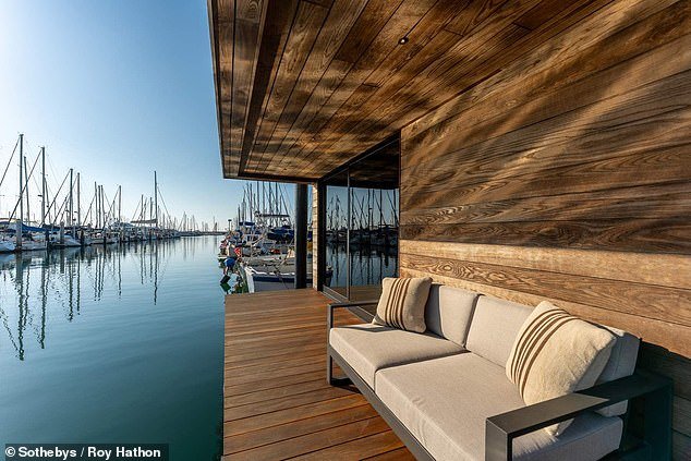 A wooden deck terrace offers views of the harbor and the water lapping at your feet