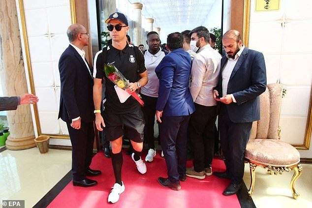 Wearing sunglasses and holding a few roses, Ronaldo arrives at Tehran airport