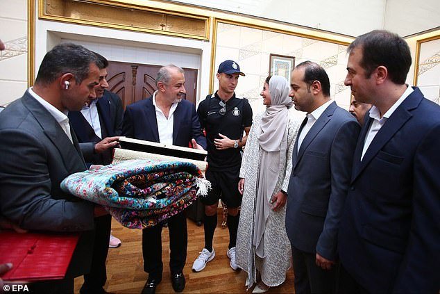 Ronaldo talks to Persepolis officials while receiving a traditional carpet as a gift