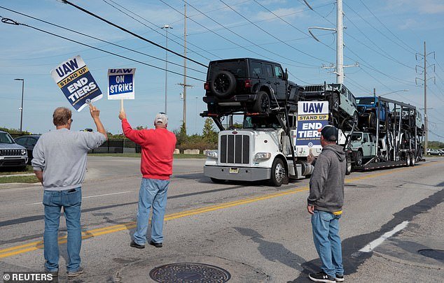 Picketers hold signs as a truck carrying Jeep Wranglers drives past the factory in Toledo, Ohio, on Sunday