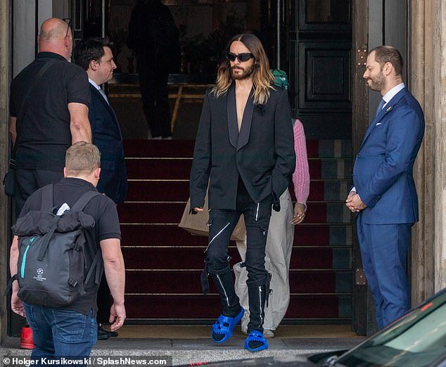 Strange look: Leto wore a loose-fitting tuxedo jacket and black pants with a zipper and his sliders