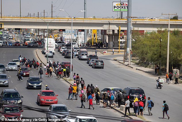 While the program is still in development, migrants continue to arrive en masse at the southern border between ports of entry.  Pictured: About 600 migrants arrived at the border on a freight train on Wednesday and marched through the streets of Ciudad, Juarez to cross into the US in El Paso, Texas