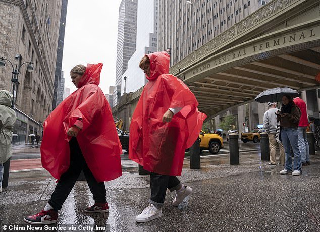 People wearing raincoats walk on the street on a rainy day in NYC