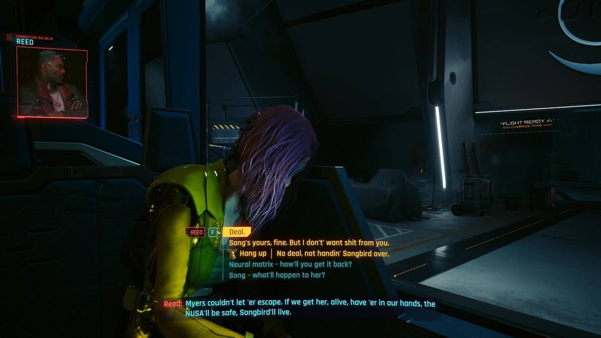 Songbird sits at a desk in a dark room during one of the endings of Cyberpunk 2077 Phantom Liberty.