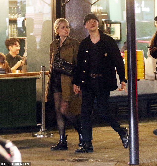Stylish: Lucy wore a khaki trench coat over a short black dress which she wore with black tights and boots