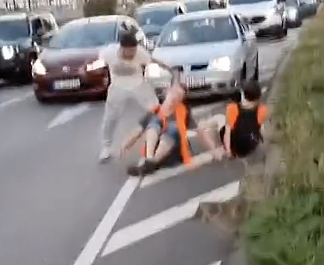 The enraged motorists grab the protester's hair before hitting him in the face with his fist
