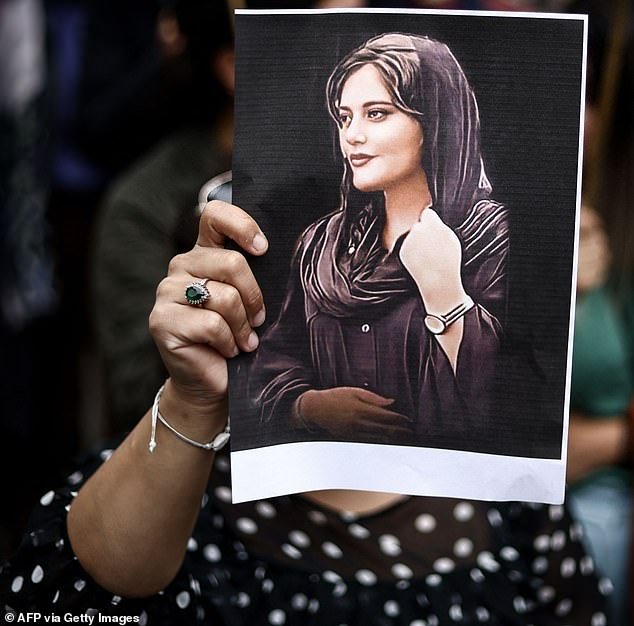 Demonstration: A protester is pictured holding a photograph of Mahsa during a demonstration outside the Iranian embassy in Brussels last year