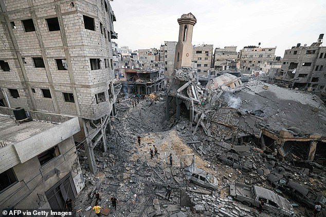 People stand among the ruins of a mosque destroyed during Israeli airstrikes, in Gaza City on October 9, 2023