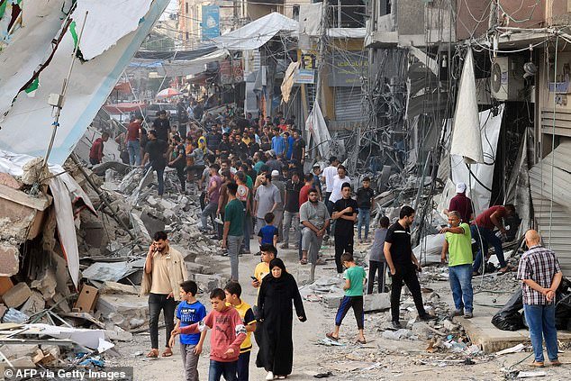 Palestinians walk among the rubble of destroyed buildings in Khan Yunis in the Gaza Strip