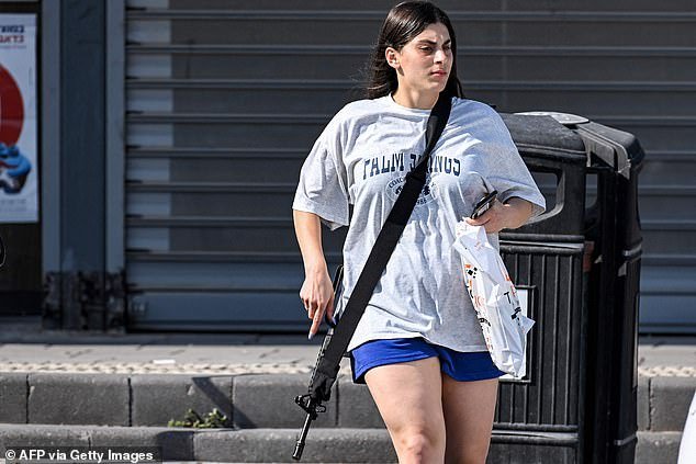 The young woman, who was wearing a baggy gray T-shirt, dark blue shorts and mats was seen carrying a duffel bag in her car with the rifle slung over her shoulder
