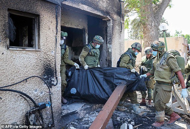 Soldiers remove the bodies of victims killed during an attack by Hamas terrorists in Kfar Azza on Tuesday