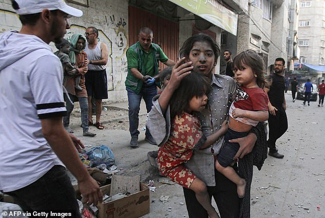 A Palestinian girl holds two children as she stands on a street in Gaza City on Thursday