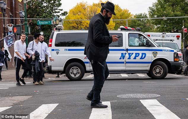 A person walks as police patrol a neighborhood in Brooklyn on Thursday.  The police are investigating incidents that happened on Wednesday that may be motivated by the war