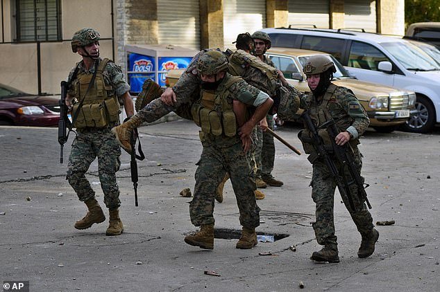 Lebanese army soldiers on Wednesday carry a wounded colleague who was injured during a demonstration, in solidarity with the Palestinian people in Gaza, near the US embassy in Awkar, a northern suburb of Beirut, Lebanon