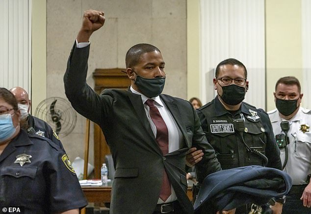 Jussie Smollett raises his fist to proclaim his innocence as he is escorted to the Leighton Criminal Courthouse during his sentencing for assault on himself in Chicago, March 10, 2022