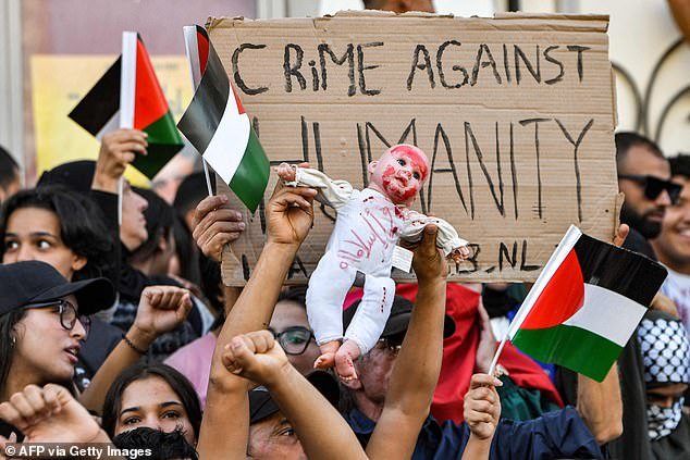 Protesters held up a doll with red paint on its face in Tunis today, along with a sign reading: 'Crime against humanity' and Palestinian flags