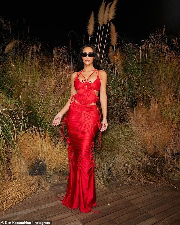 At the event, Kim wore a striking red ensemble of a fitted dress with the sides cut out and held together with bows