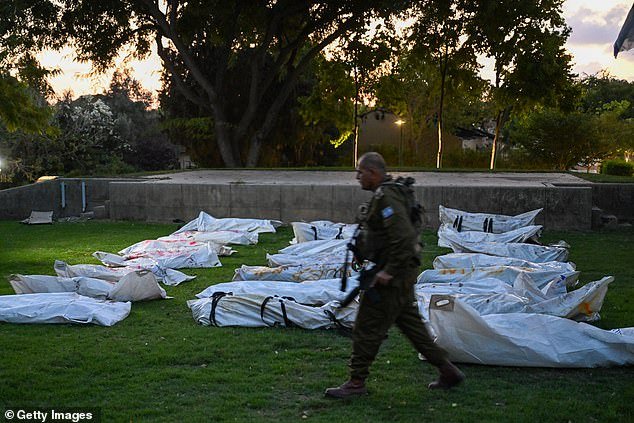 An IDF soldier walks past body bags of more than 20 dead Hamas militants with the word 