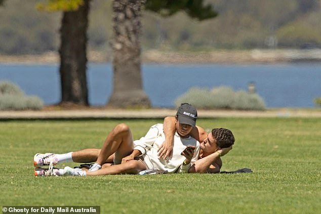 The couple looked playful as they lay on the grass, tossing empty water bottles into the air and catching them as Cleary put his arm around Fowler and laughed.