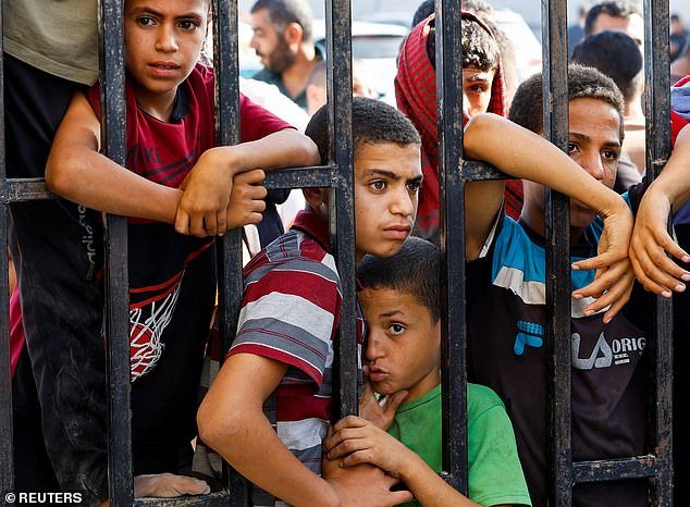 Children await the arrival of Palestinian workers, who were in Israel during the October 7 Hamas attack, at the Rafah border after being sent back to the strip by Israel, in the southern Gaza Strip, on November 3