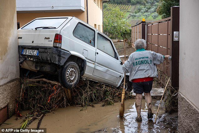 A woman tries to clear the mud in Montemurlo near Prato after heavy rain last night, on November 3, 2023