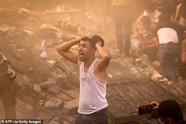 A Palestinian man reacts as others check the rubble of a building in Khan Yunis on November 6