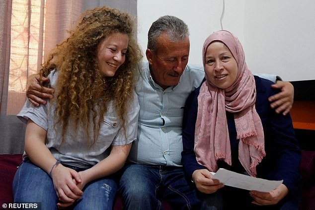 Ahed Tamimi sits next to her father and her mother Nareman, who were released with her from an Israeli prison, at their family home in the village of Nabi Saleh on July 30, 2018