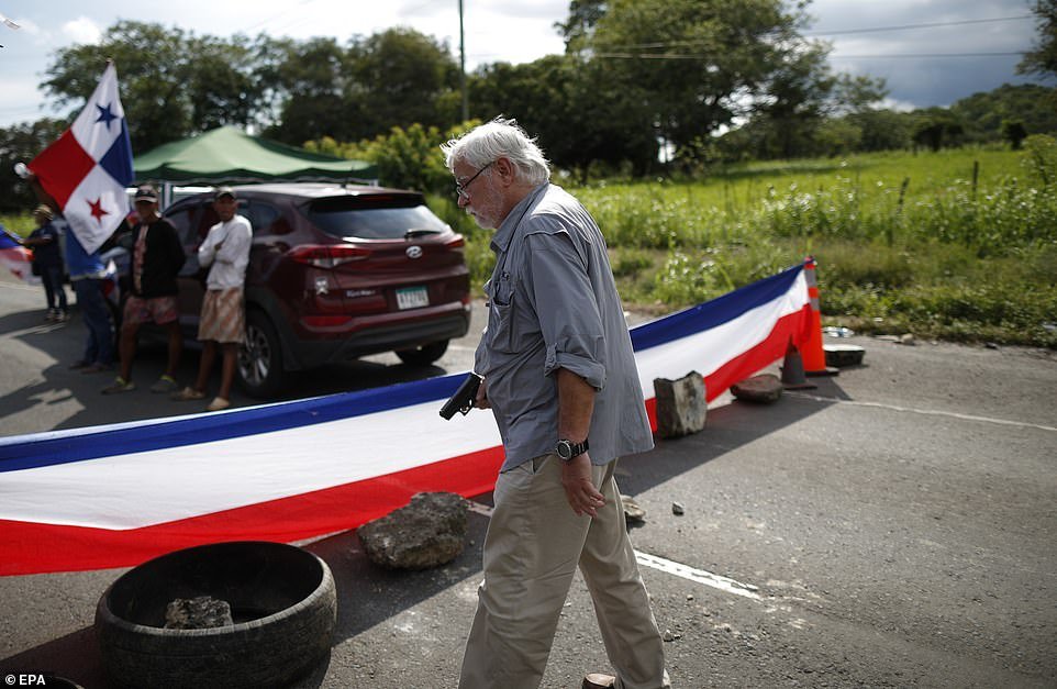 A man is seen holding a gun after walking toward a teacher blockade on the Pan-American Highway in Chame