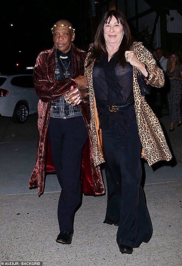 Stylish: Huston looked stunning in a black sheer blouse and flared trousers, paired with a leopard print jacket as she arrived on a friend's arm