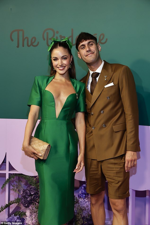 The former Miss Universe Australia winner, 31, had her hair styled in a preppy, hall ponytail that was tied with a matching green bow.  Pictured with Paul Versace