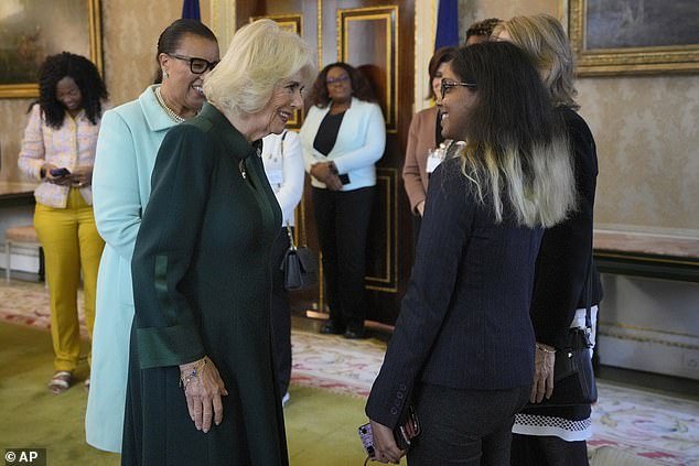 Camilla speaks to Maya Kirti Nanan as she wears a dark green dress and heeled boots at today's event