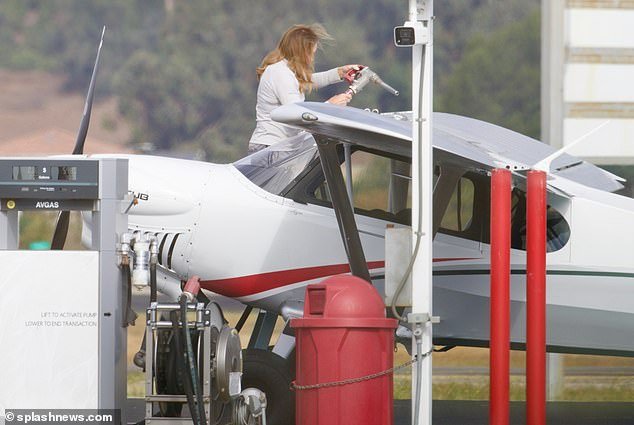 Fill: The star cut a casual figure in a gray sweater paired with slate joggers as she climbed a ladder to refuel the plane for an afternoon of flying