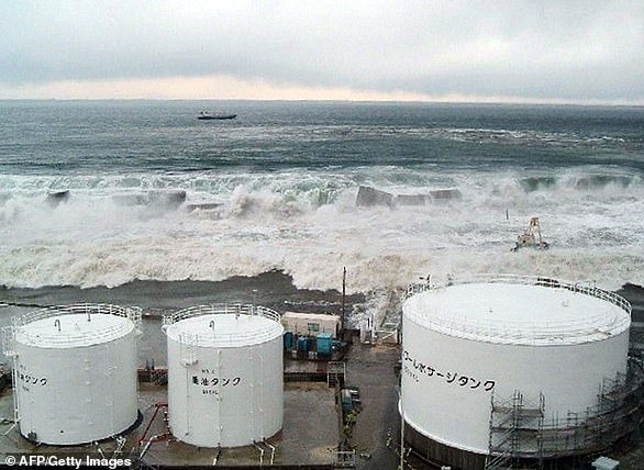 Tsunami waves crash over the sea wall towards TEPCO's Fukushima Daiichi nuclear power plant in Okuma