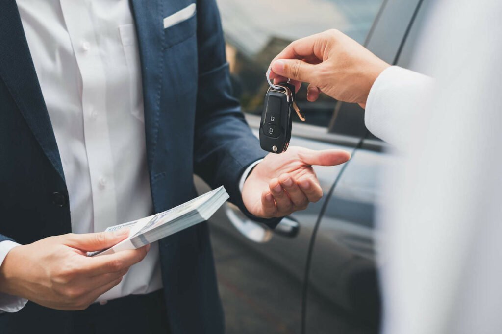 Closeup Photo Of Two Hands Exchanging Car Keys And Cash