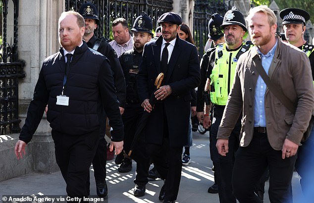 A smartly dressed David Beckham queues for thirteen hours to see Queen Elizabeth lie in state at Westminster Hall